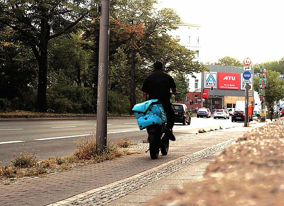Lieferdienst-Fahrer:innen arbeiten oft unter prekären Bedingungen Lieferdienst-Fahrer auf dem Fahrrad transportiert eine Wolt-Transport-Box auf dem Gepäckträger