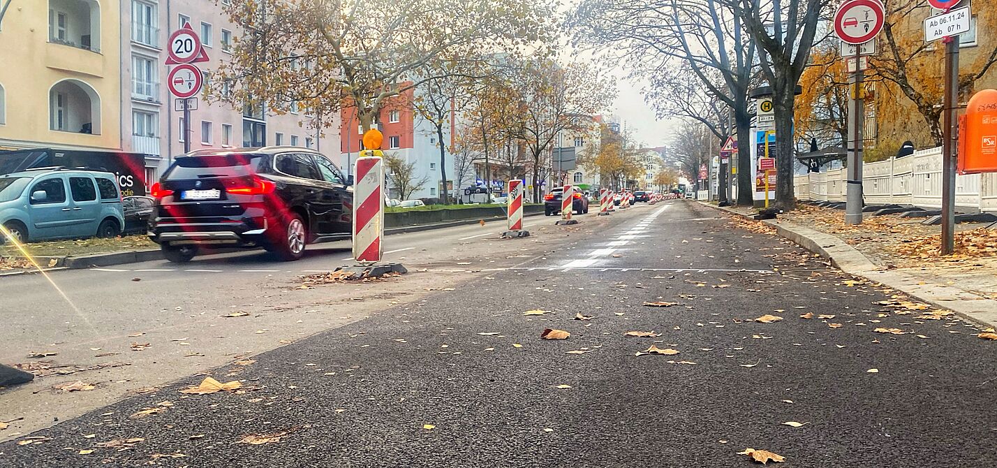 Zwischen Martin-Luther-Straße und Bayerischem Platz ist eine frisch asphaltierte Fahrbahn am rechten Rand durch einen weißen Streifen und Baken von der Spur für Autos weiter in der Mitte abgegrenzt. 