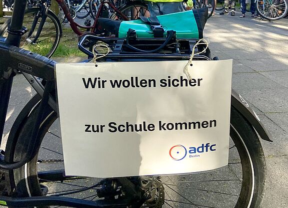 Auf einem Schild des ADFC Berlin für eine Fahrraddemo auf der Marienfelder Allee steht: "Wir wollen sicher zur Schule kommen"