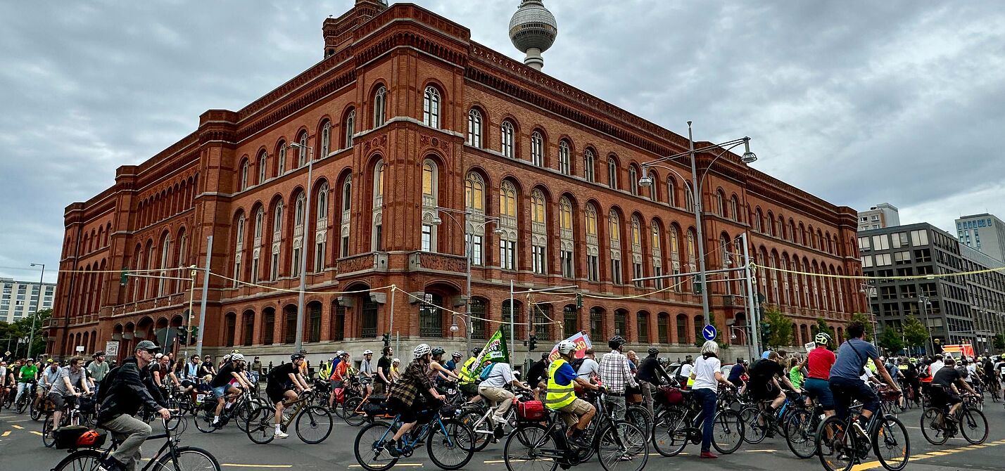 Menschen fahren bei einer Fahrrademonstration um das Rote Rathaus